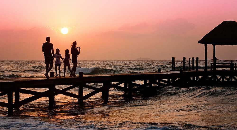 Familie auf einem Pier bei Sonnenuntergang